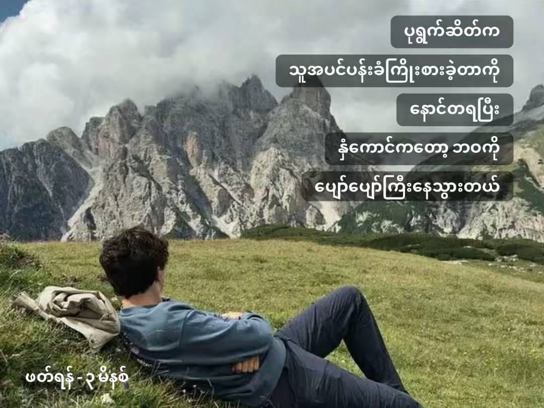 Person lying on the grass looking at mountains